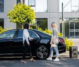 Women entering black sedan